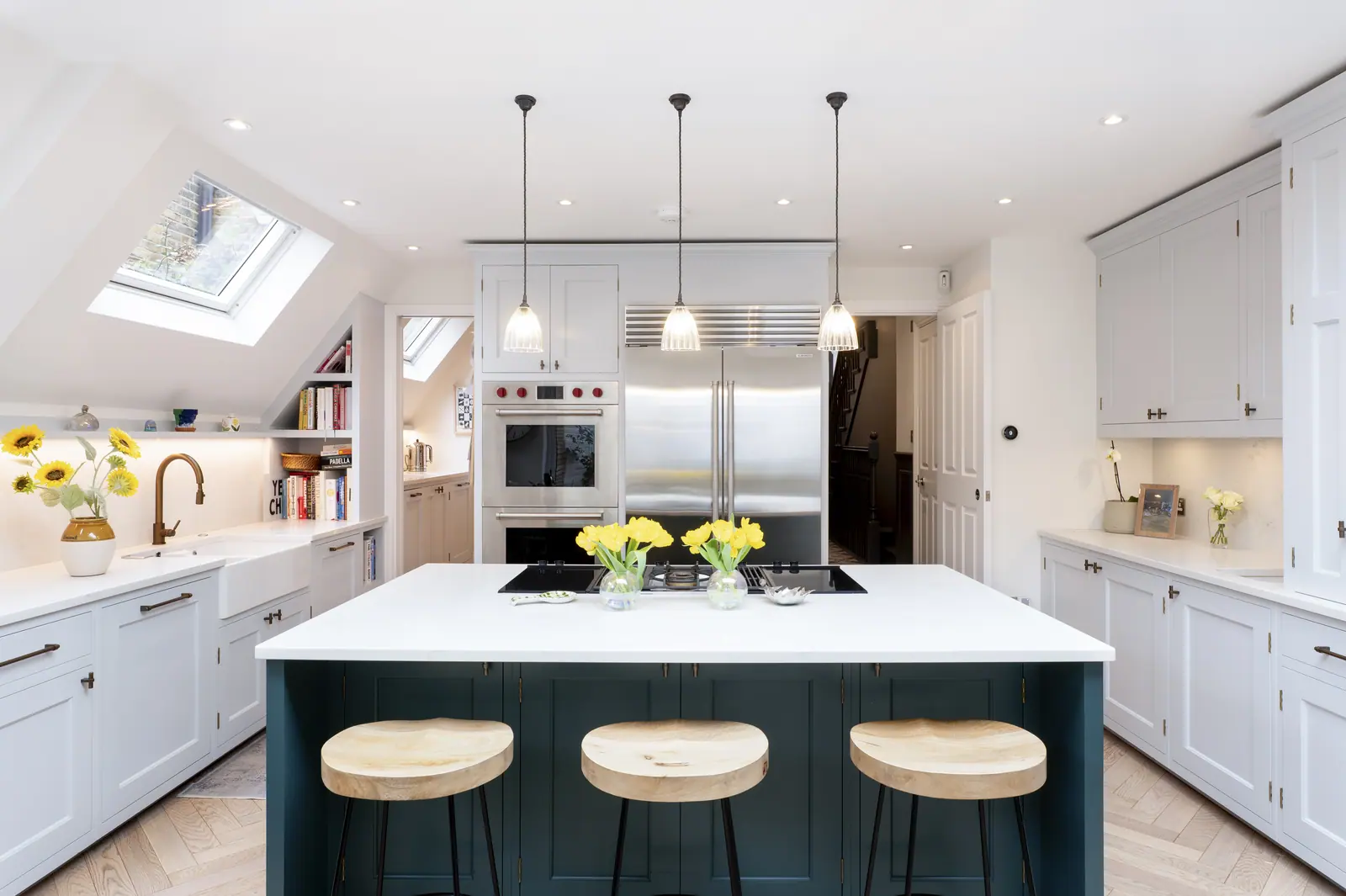Hand-painted Shaker kitchen in off-white, with a dark blue island seating three.