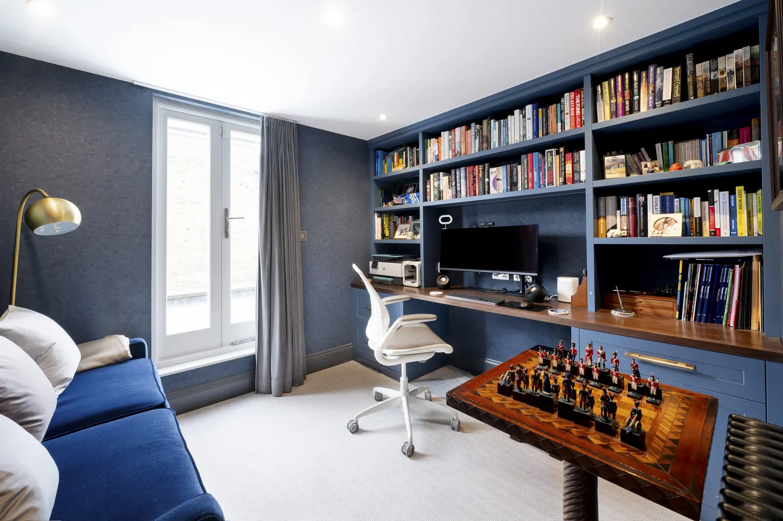The study as a room: desk under the window, shelving along the wall and space to sit.