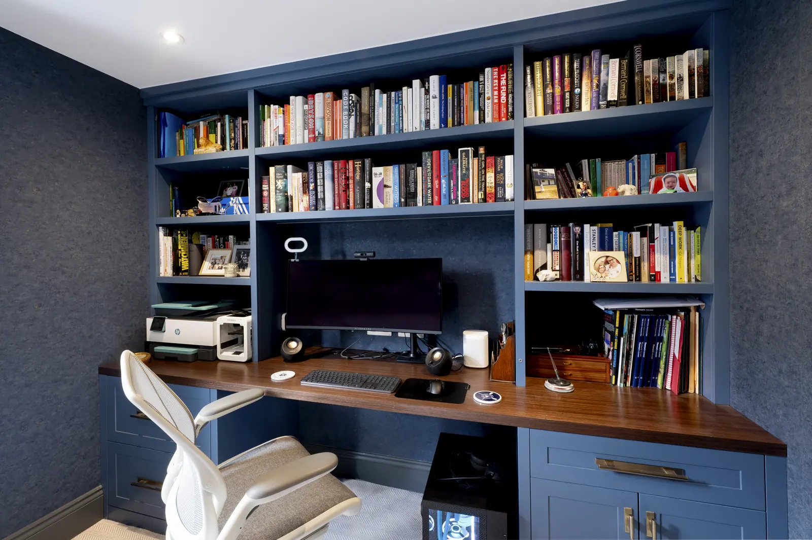 The desk wall seen from the door, with lighting set under the shelves.