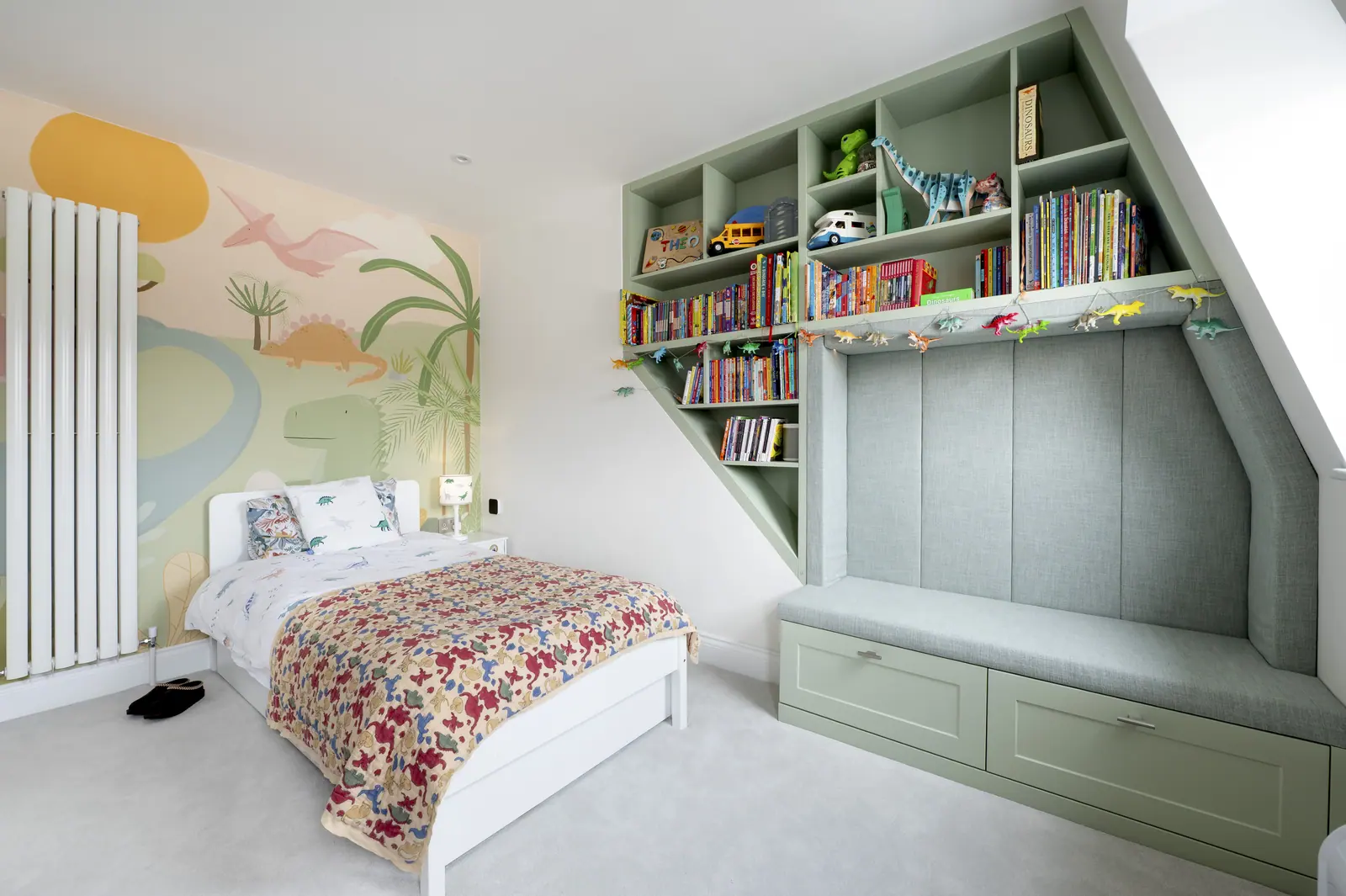 A child's room with a window seat, drawers underneath and shelving over the bed.