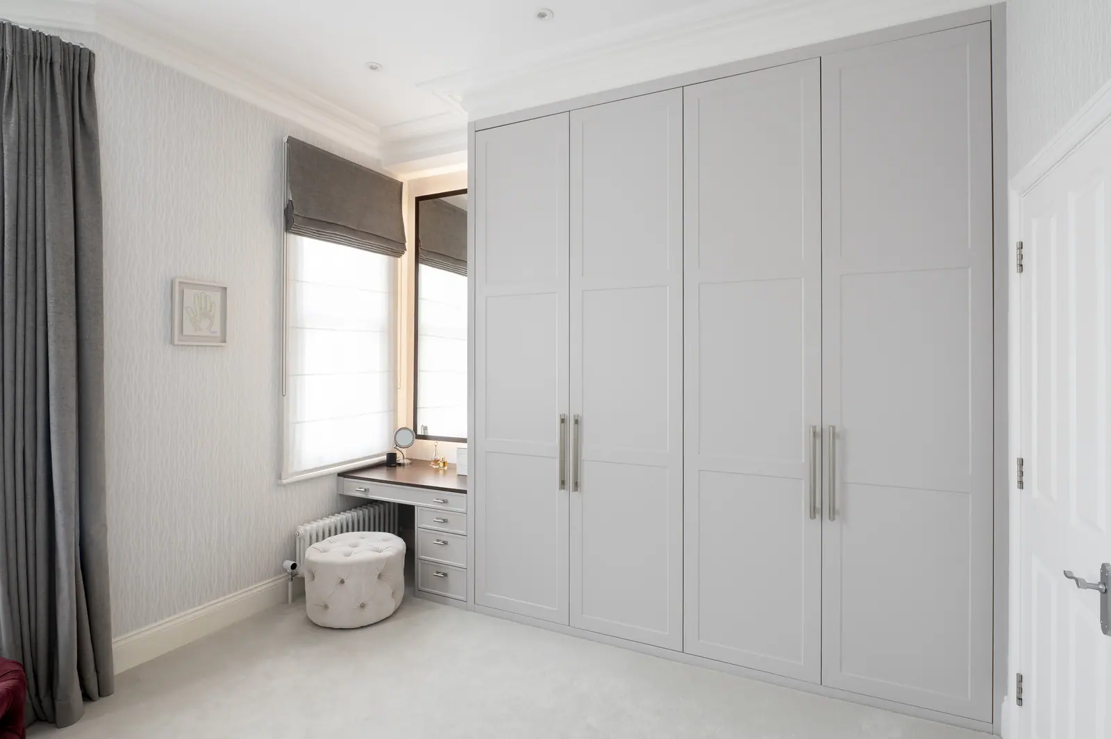 Floor-to-ceiling wardrobes and a dressing table set under the window.