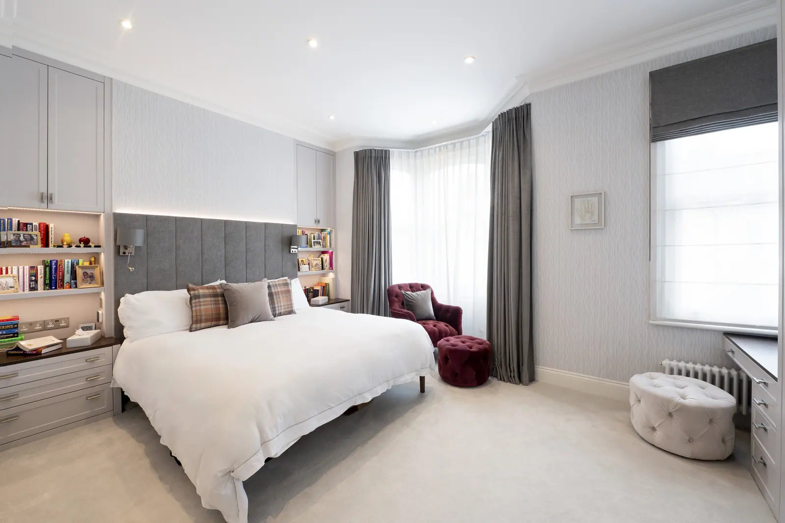 Principal bedroom in silvery grey, with shelving built into the headboard wall.