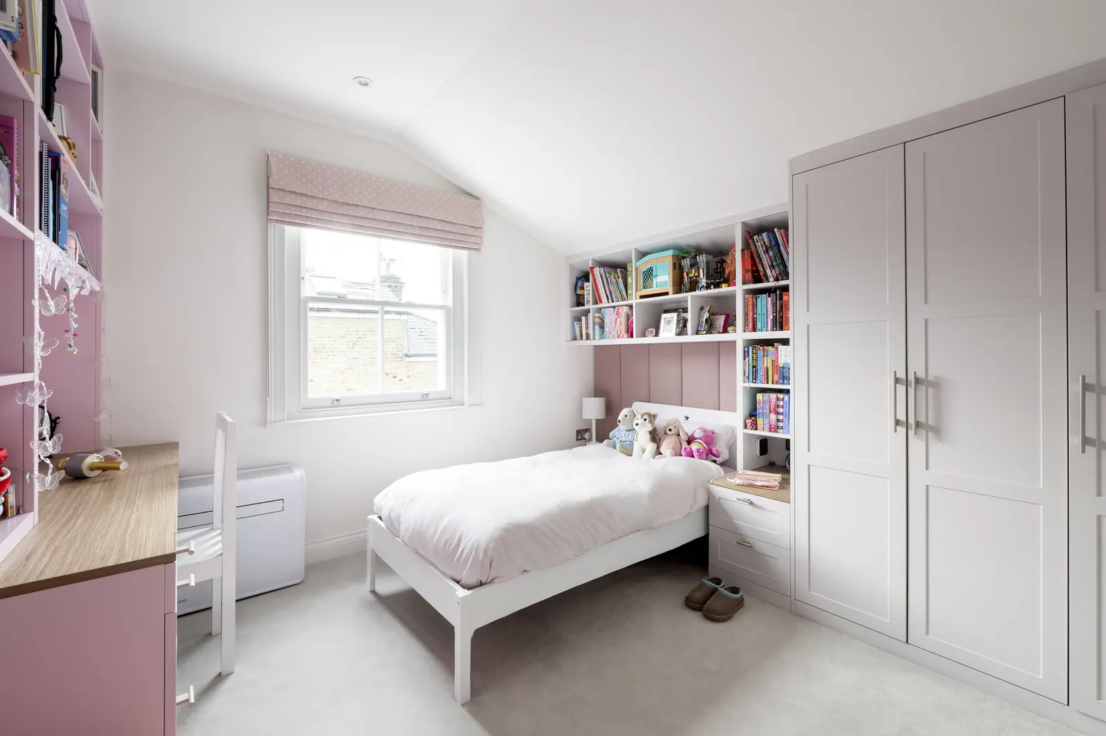 The daughter's room in soft pink, with a built-in desk and wardrobes.