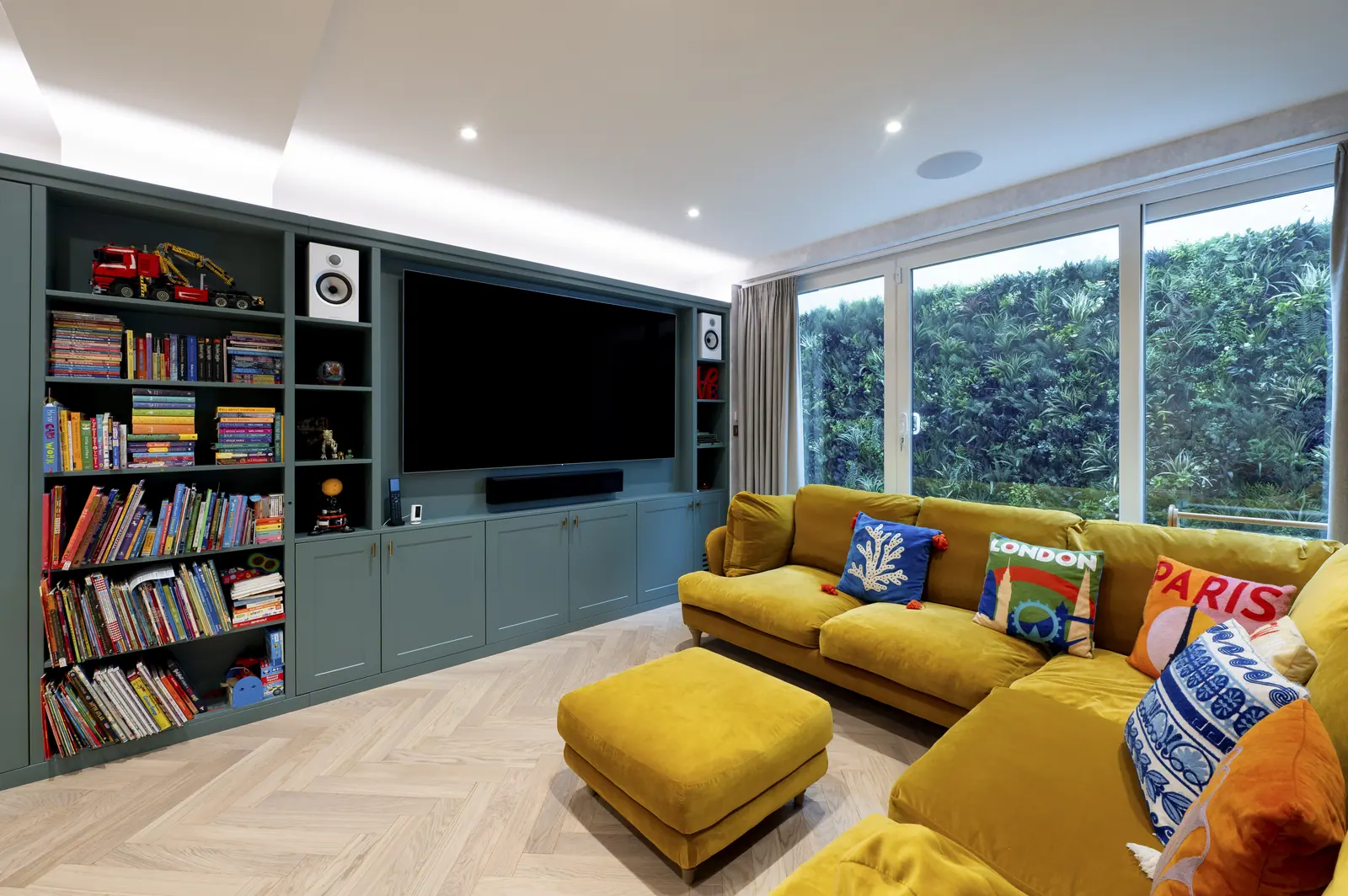 Basement family and cinema room, with green joinery wrapping the television wall.