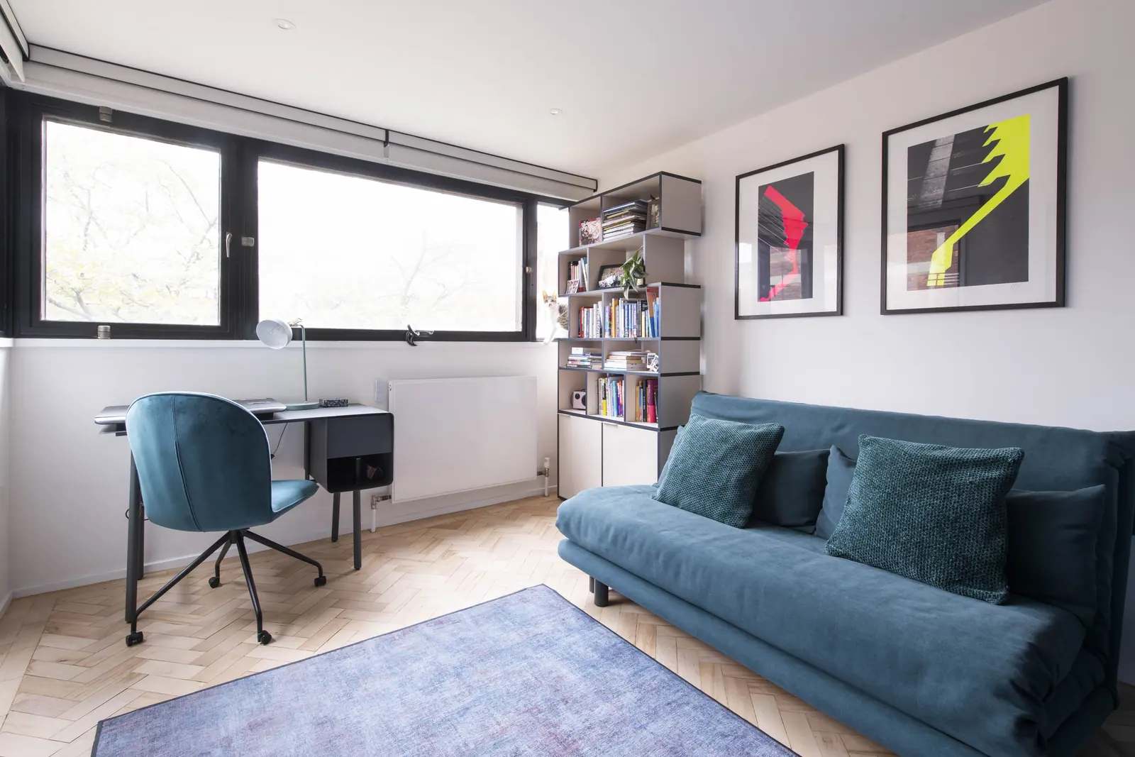 A study that doubles as a guest room: desk at the window, shelving alongside.